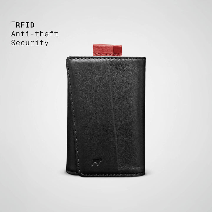 Black leather wallet with red pull tab on a light gray background, featuring &
