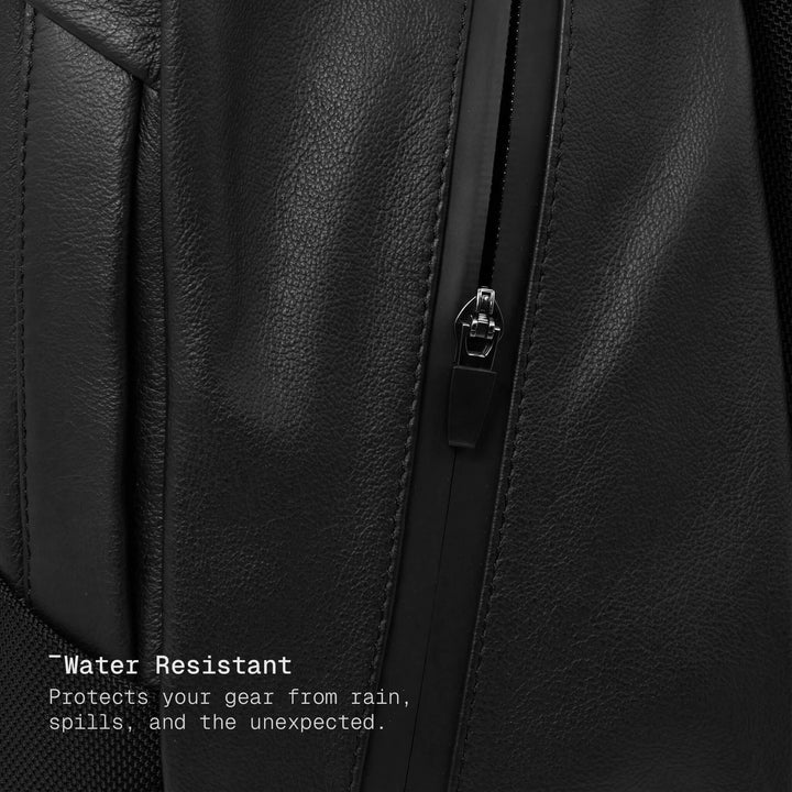 Close-up of a black leather backpack with a zipper, highlighting water resistance feature.