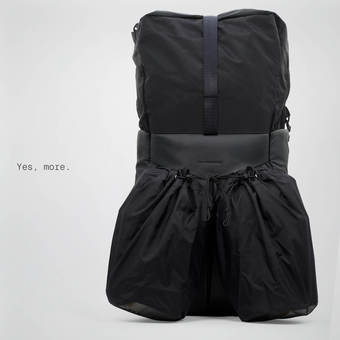 Black backpack with a drawstring at the bottom on a light gray background