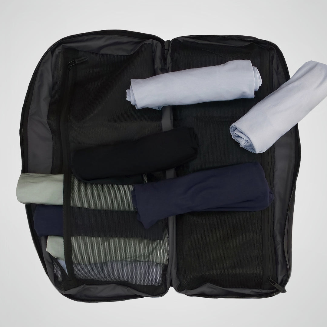 Black suitcase with folded clothes inside on a white background