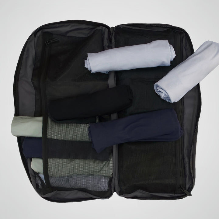 Black suitcase with folded clothes inside on a white background