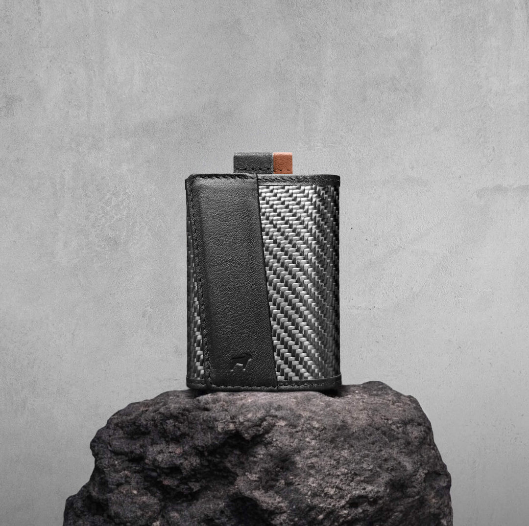 Black and carbon fiber patterned rectangular device on a gray rock with a gray background